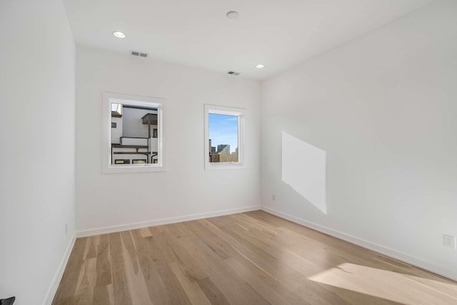 spare room with light wood-type flooring, visible vents, baseboards, and recessed lighting