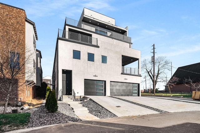 contemporary house featuring a balcony, stucco siding, driveway, and a garage