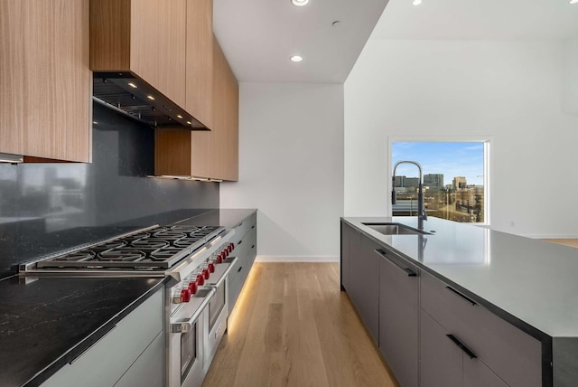 kitchen featuring double oven range, a sink, custom range hood, modern cabinets, and light wood-type flooring