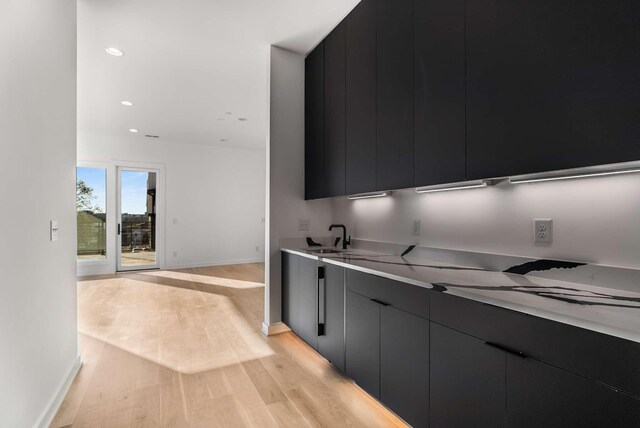 kitchen with light wood finished floors, modern cabinets, light countertops, and dark cabinets