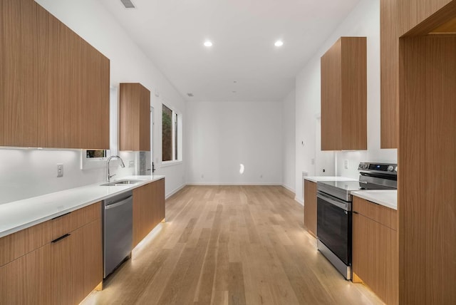 kitchen featuring modern cabinets, appliances with stainless steel finishes, light countertops, and a sink