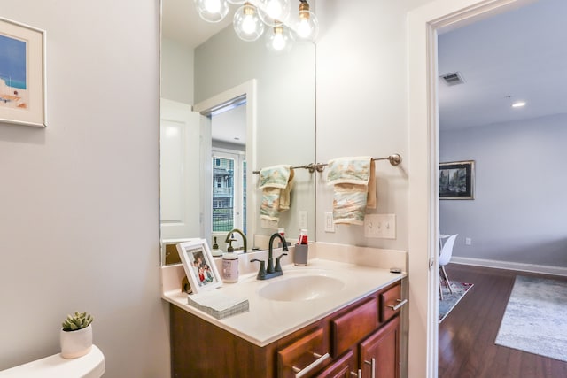 bathroom with a notable chandelier, vanity, toilet, and hardwood / wood-style floors