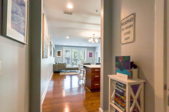 corridor with dark hardwood / wood-style flooring and an inviting chandelier