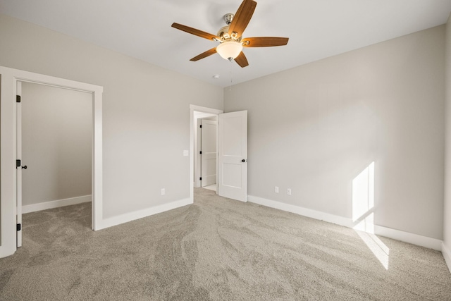 unfurnished bedroom featuring carpet, a spacious closet, and ceiling fan