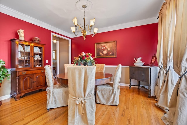 dining space featuring crown molding, an inviting chandelier, and light wood-type flooring