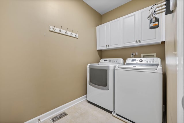 washroom featuring cabinets, light tile patterned flooring, and separate washer and dryer