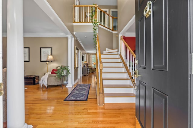 entryway with crown molding, light hardwood / wood-style flooring, and ornate columns