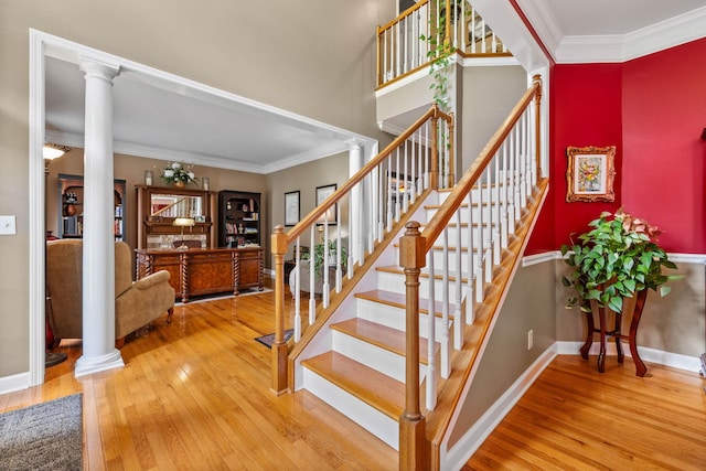 staircase featuring ornamental molding, wood-type flooring, and decorative columns