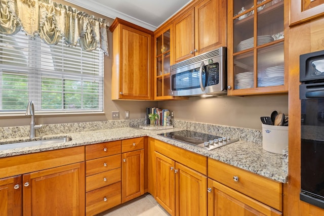 kitchen with light tile patterned flooring, sink, black electric stovetop, and light stone counters