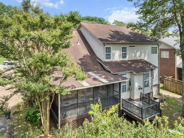 rear view of property featuring a sunroom and a deck