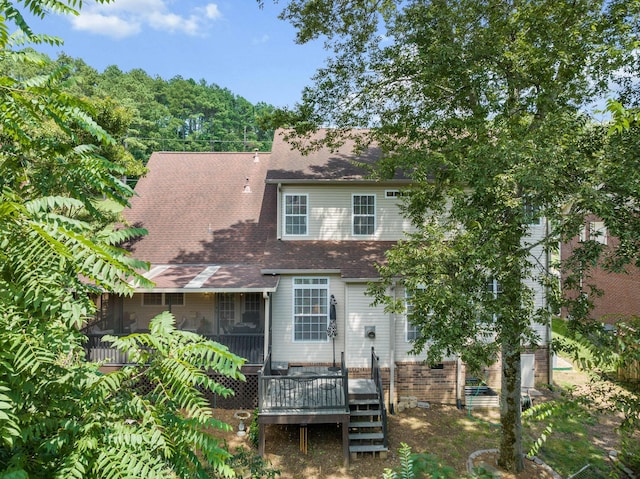 back of property with a wooden deck and a sunroom