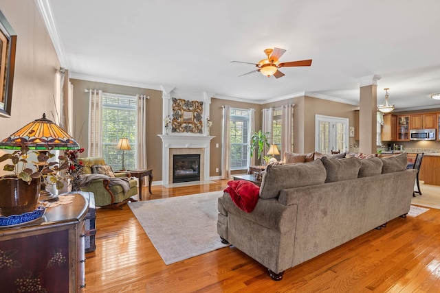 living room featuring crown molding, ceiling fan, a tile fireplace, and light wood-type flooring