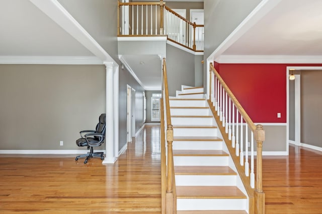 stairs featuring a high ceiling, ornamental molding, and hardwood / wood-style floors