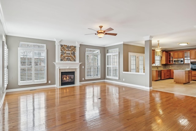 unfurnished living room with ceiling fan, ornamental molding, sink, and light wood-type flooring