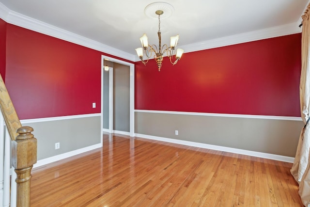 unfurnished room featuring an inviting chandelier, wood-type flooring, and ornamental molding