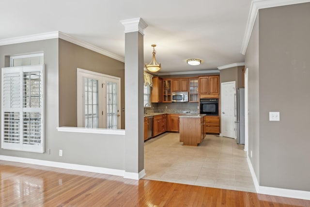 kitchen featuring appliances with stainless steel finishes, hanging light fixtures, a center island, ornamental molding, and ornate columns