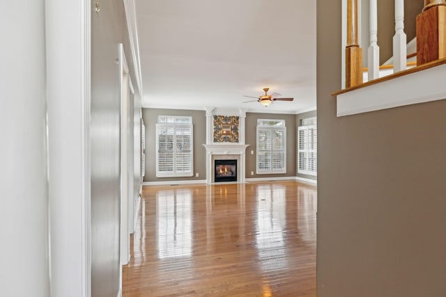 unfurnished living room featuring crown molding, plenty of natural light, ceiling fan, and light hardwood / wood-style floors