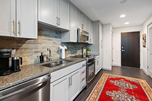 kitchen with sink, dark wood-type flooring, stainless steel appliances, and dark stone counters