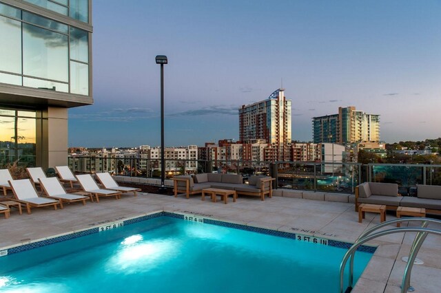 pool at dusk featuring a patio and an outdoor living space