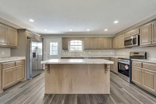 kitchen featuring a kitchen island, appliances with stainless steel finishes, sink, hardwood / wood-style flooring, and a textured ceiling