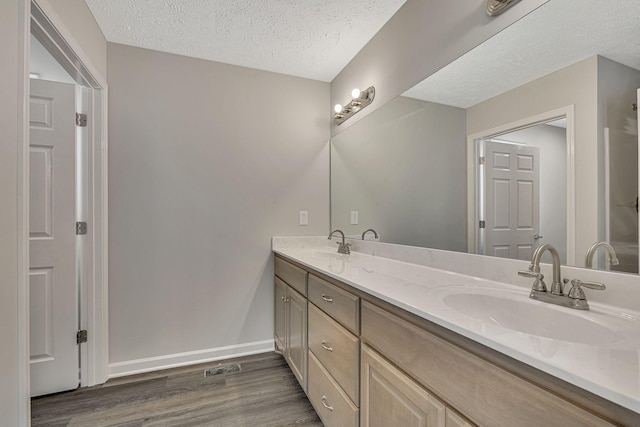 bathroom with vanity, hardwood / wood-style floors, and a textured ceiling