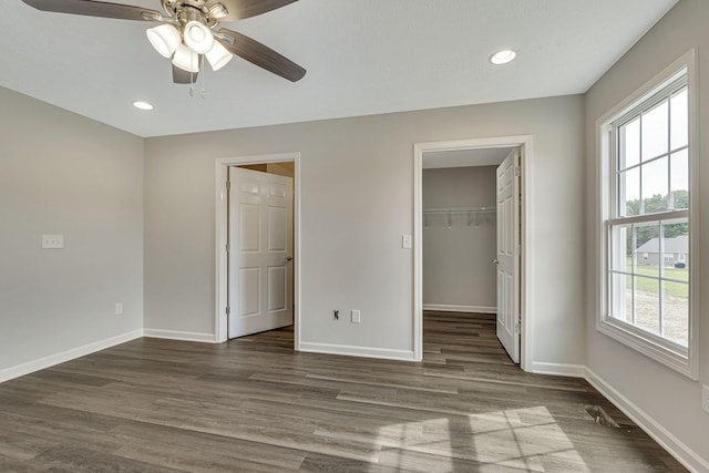 unfurnished bedroom with ceiling fan, dark hardwood / wood-style floors, a closet, and a spacious closet