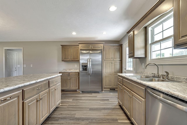 kitchen with stainless steel appliances, sink, a textured ceiling, and light wood-type flooring