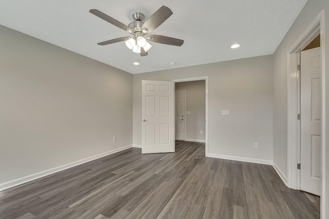 empty room with ceiling fan, dark hardwood / wood-style flooring, and a textured ceiling