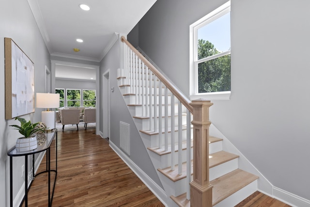 staircase with wood-type flooring and ornamental molding