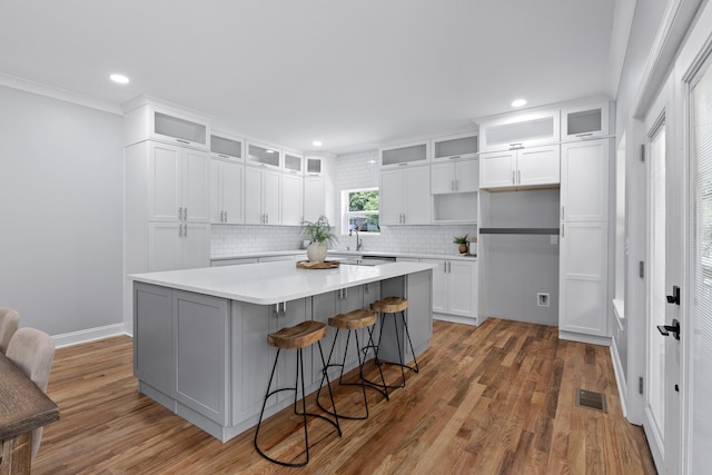 kitchen featuring wood-type flooring, white cabinets, a kitchen island, and backsplash