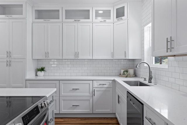 kitchen with dark hardwood / wood-style flooring, dishwasher, sink, tasteful backsplash, and white cabinetry