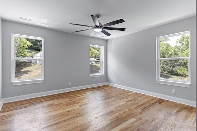 spare room with ceiling fan, a healthy amount of sunlight, and light hardwood / wood-style floors