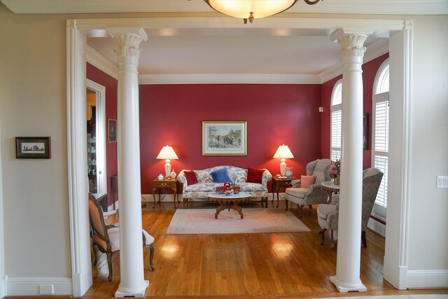 living room with decorative columns, light wood-type flooring, and ornamental molding