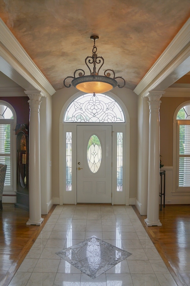 foyer with light hardwood / wood-style floors, ornate columns, and ornamental molding