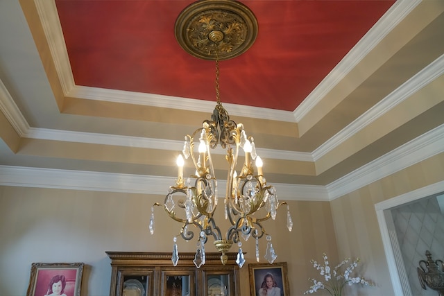 details featuring a chandelier, a raised ceiling, and ornamental molding