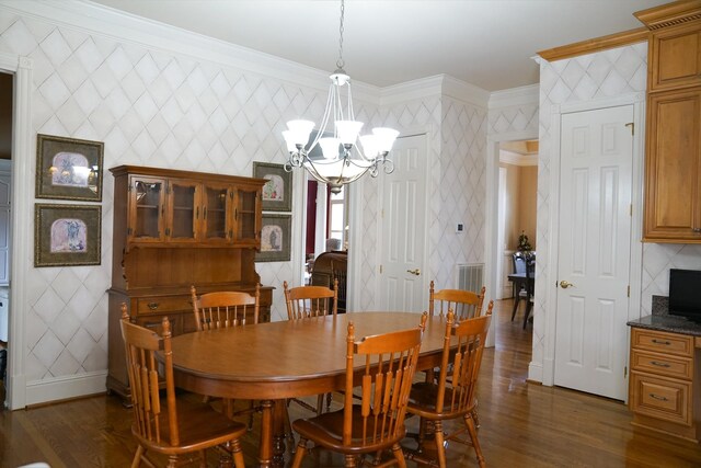 dining space featuring an inviting chandelier, crown molding, and dark wood-type flooring