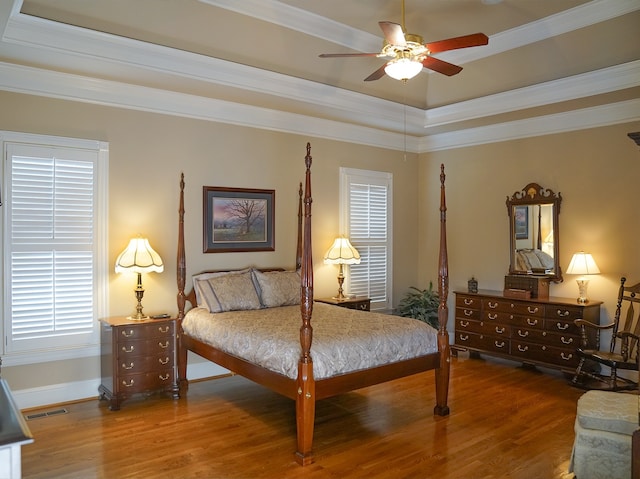 bedroom featuring ceiling fan, crown molding, a tray ceiling, and wood-type flooring