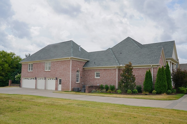 view of property exterior with a garage, central air condition unit, and a yard