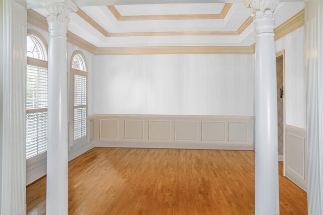 unfurnished room featuring crown molding, a tray ceiling, ornate columns, and light hardwood / wood-style floors