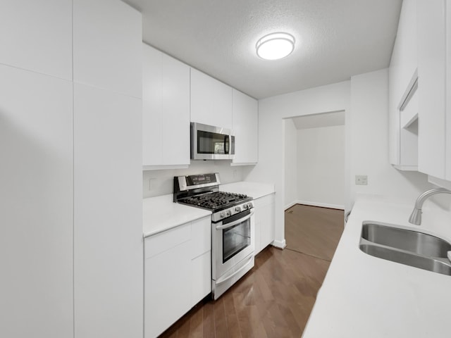 kitchen with a textured ceiling, appliances with stainless steel finishes, white cabinets, and sink