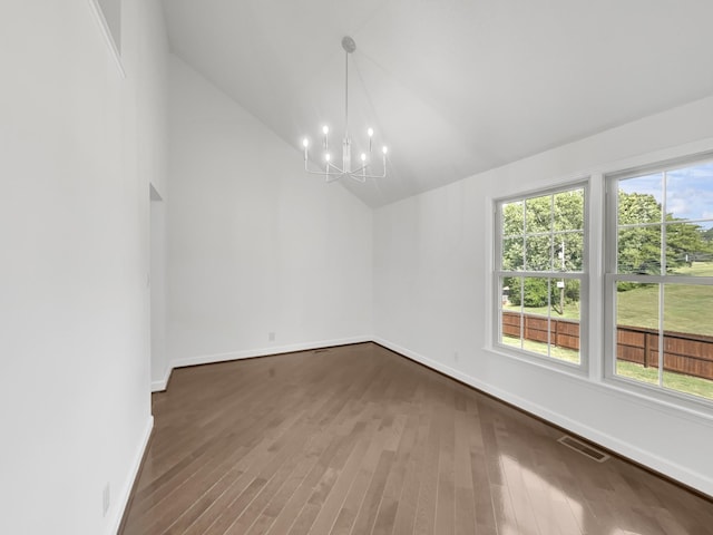 spare room featuring a chandelier, wood-type flooring, and high vaulted ceiling