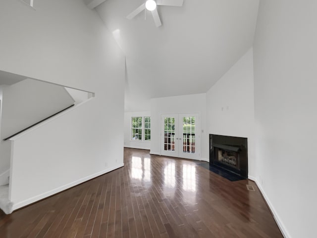 unfurnished living room with ceiling fan, dark hardwood / wood-style floors, french doors, high vaulted ceiling, and beam ceiling