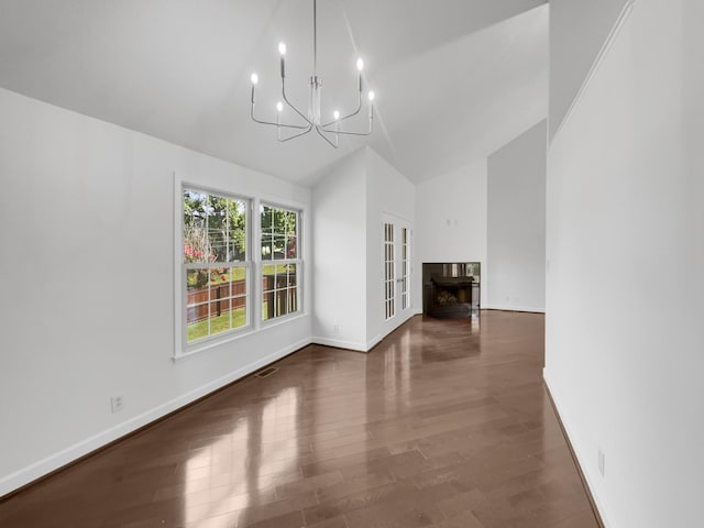 unfurnished dining area with high vaulted ceiling, dark hardwood / wood-style floors, and an inviting chandelier