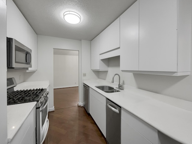 kitchen with a textured ceiling, white cabinets, stainless steel appliances, sink, and dark hardwood / wood-style floors