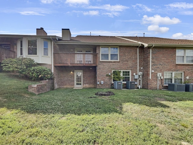 back of property featuring a balcony, central AC, and a yard