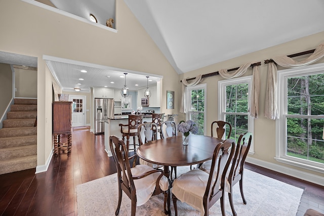 dining room with high vaulted ceiling and dark hardwood / wood-style floors