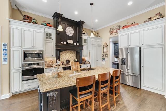 kitchen featuring stainless steel appliances, decorative backsplash, crown molding, light hardwood / wood-style floors, and a kitchen island with sink