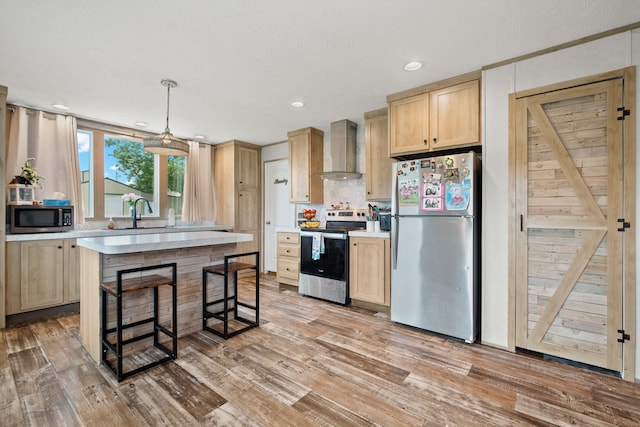 kitchen featuring stainless steel appliances, sink, light hardwood / wood-style floors, light brown cabinetry, and wall chimney exhaust hood