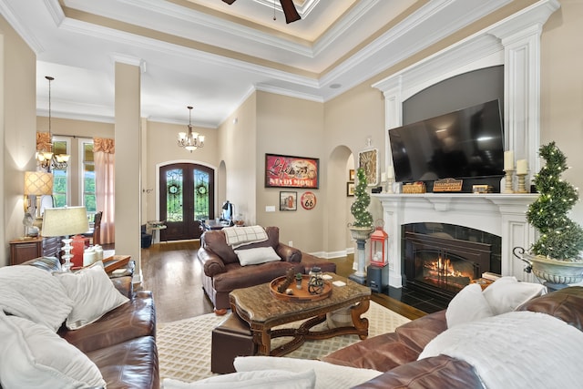 living room featuring hardwood / wood-style floors, an inviting chandelier, french doors, ornate columns, and ornamental molding