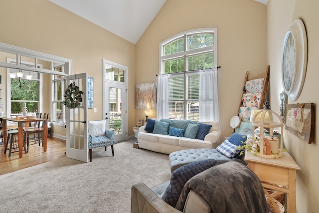 carpeted living room featuring high vaulted ceiling, french doors, and plenty of natural light